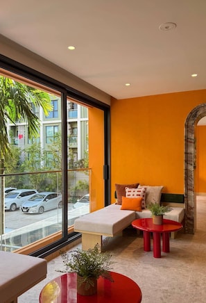 A modern room with a large window, a sofa, a red table, and a bench. - 2-bed at The Base Rise, Near Central Phuket (Wichit)