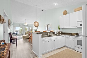 A modern kitchen with white cabinetry, granite countertops, and a central island. - 10% off 3-7 nights thru Dec. 2BR 2BA condo. Lake view, gated comm. Short walk to beach. (North Myrtle Beach)
