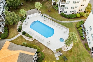 An aerial view of a residential area with a swimming pool surrounded by a white fence, a small garden, and adjacent buildings. - 10% off 3-7 nights thru Dec. 2BR 2BA condo. Lake view, gated comm. Short walk to beach. (North Myrtle Beach)