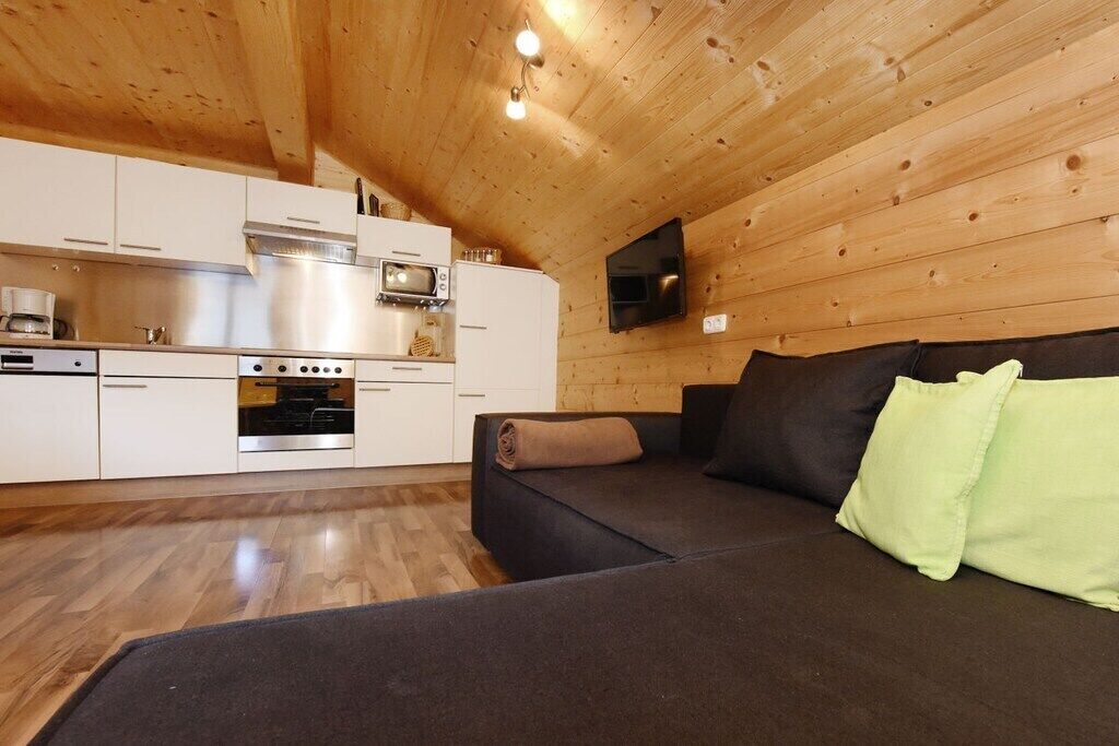Eine moderne Küche mit Edelstahlgeräten, einer Holzbalkendecke und einem flachbildfernseher an der Wand.