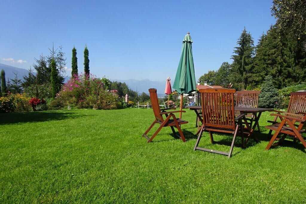 A grassy outdoor area with wooden furniture and a green umbrella.