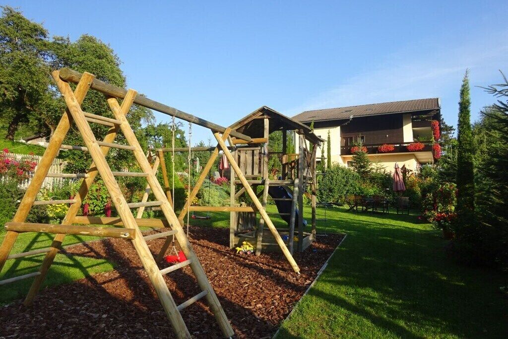 Una construcció de fusta per jugar en un jardí, amb una casa al fons.