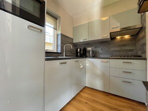 A modern kitchen with white cabinets, a stainless steel range hood, and a window providing natural light.