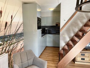 A modern interior with a kitchen, a staircase, and a seating area.