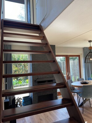 A modern interior with a wooden staircase leading to a dining area.
