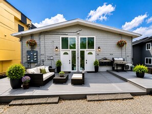 A residential building with a covered patio area featuring outdoor furniture and potted plants.
