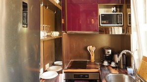Cocina compacta con refrigerador, microondas, estufa y pileta.