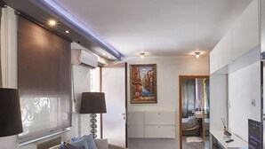 Un dormitorio moderno con una cama grande, mesitas de noche, un cuadro y un televisor.