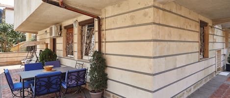 An outdoor seating area with a table and chairs, a potted plant, and a decorative metal gate.