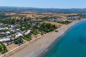 Vue aérienne d’une ville côtière avec une plage, des immeubles résidentiels et une mer bleue et limpide.