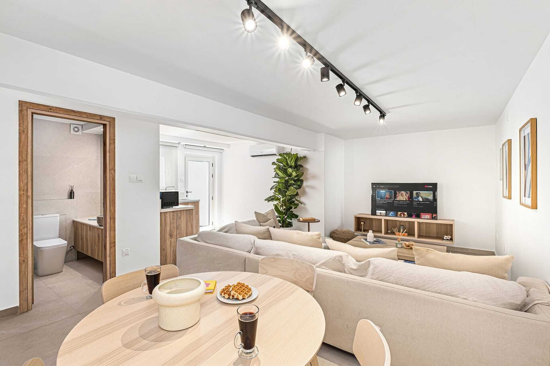 Un salon moderne avec un canapé, une table basse et un téléviseur.