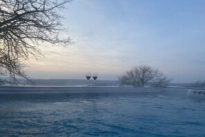 A pool with two wine glasses on the edge, surrounded by bare trees and a clear sky. - Holiday home with 2 bedrooms (Litzelsdorf)