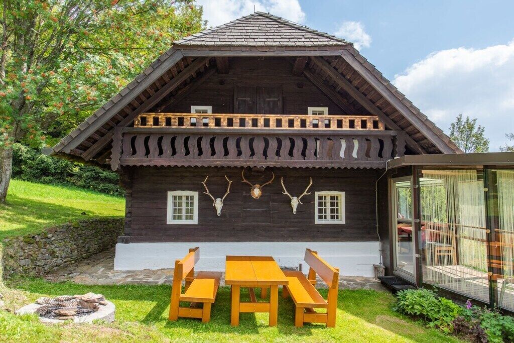 A wooden cabin with a balcony, a dining table, and benches.