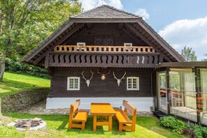 A wooden cabin with a balcony, a dining table, and benches. - Holiday home in Anger with swimming pool (Anger)