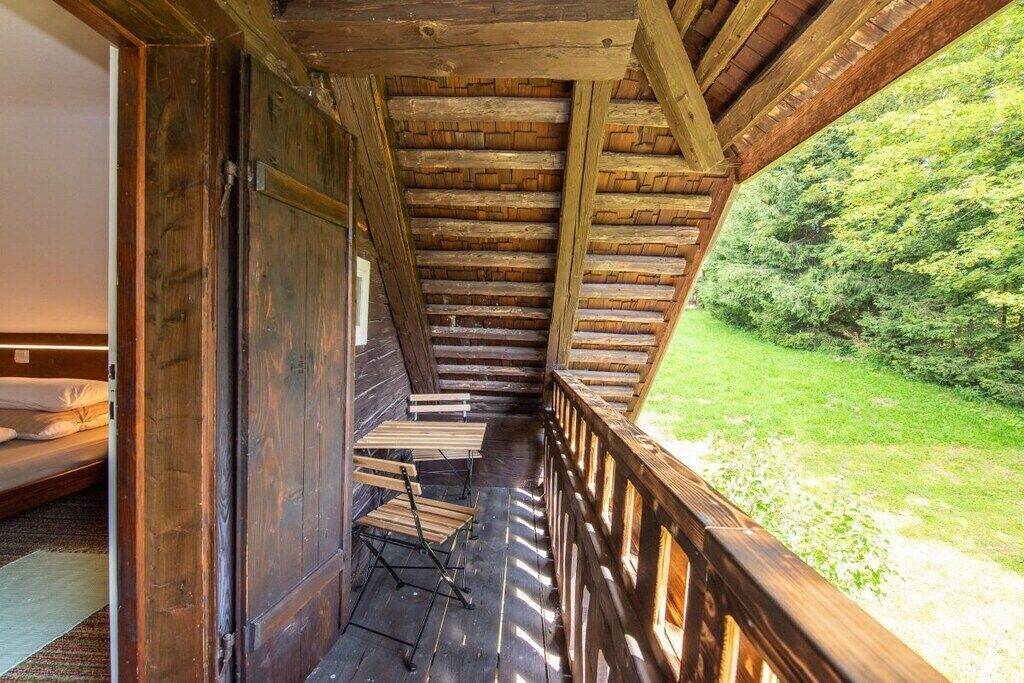 Een houten balkon met uitzicht op een grasveld en bomen.
