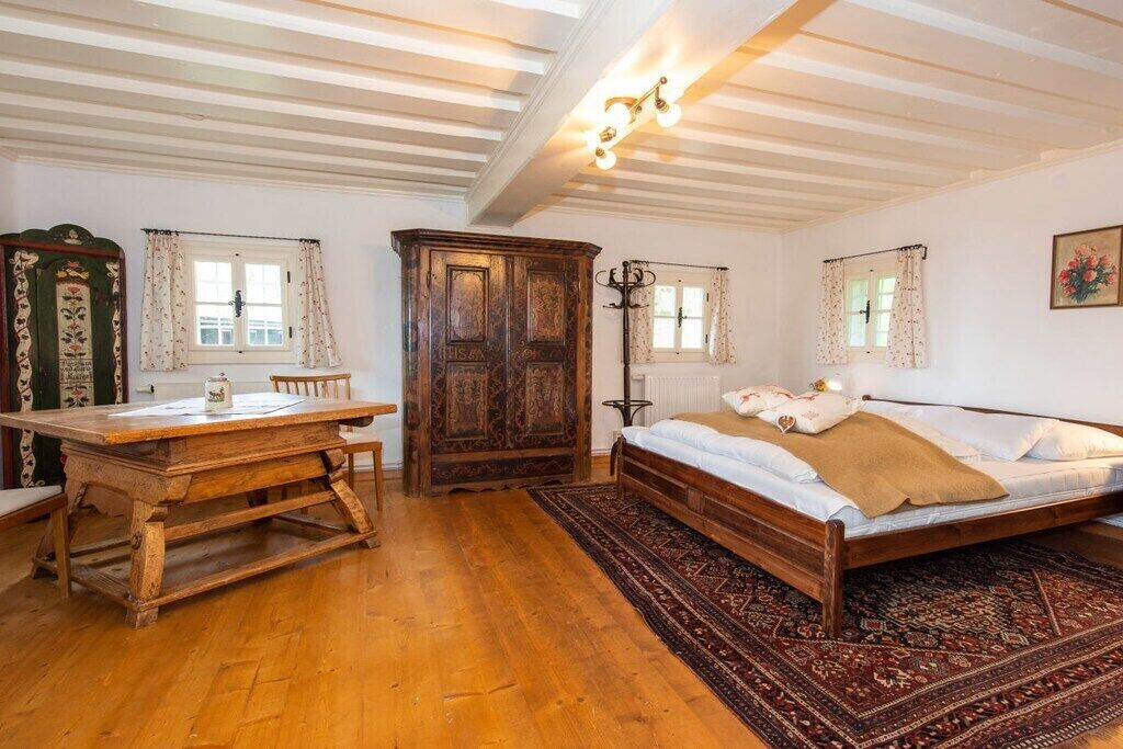 A bedroom with a wooden bed, a wooden desk, and a large wardrobe.