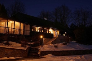 A house with a large glass facade, a visible staircase leading to the entrance, and a snow-covered ground. - Holiday home in Anger with swimming pool (Anger)