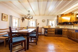 A rustic kitchen with wooden cabinets, a dining table with chairs, and a chandelier. - Holiday home in Anger with swimming pool (Anger)