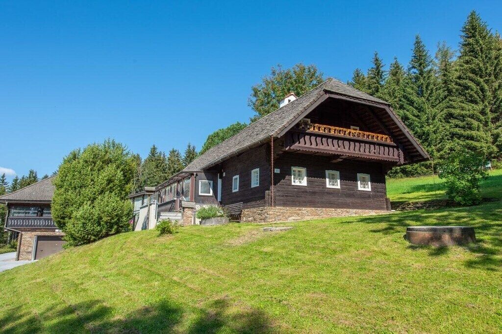 A traditional wooden chalet with a sloped roof, a balcony, and a stone foundation.