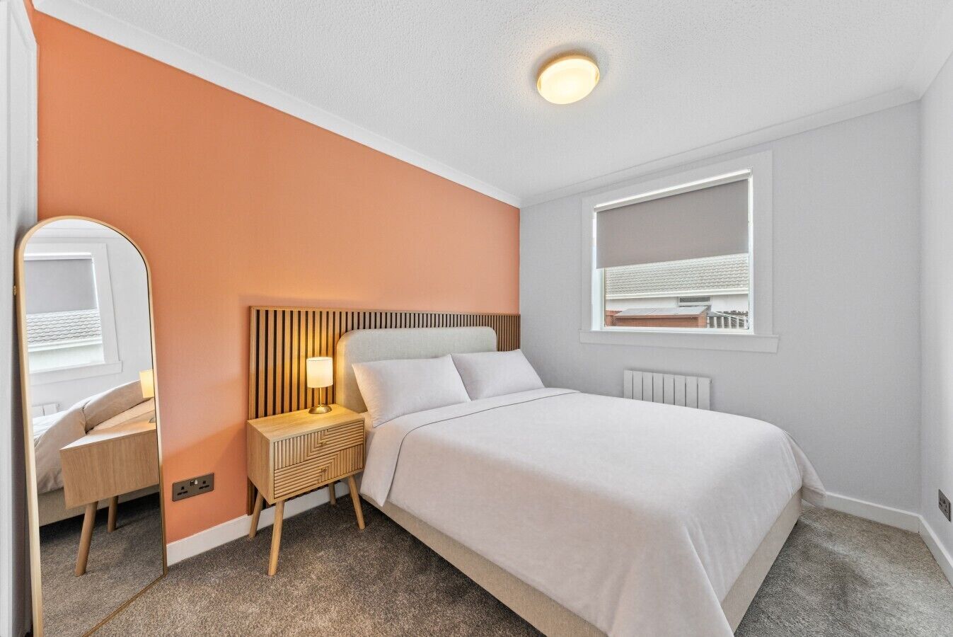 Une chambre d’hôtel avec un lit, une table de chevet, une lampe et une fenêtre donnant sur un paysage agréable.