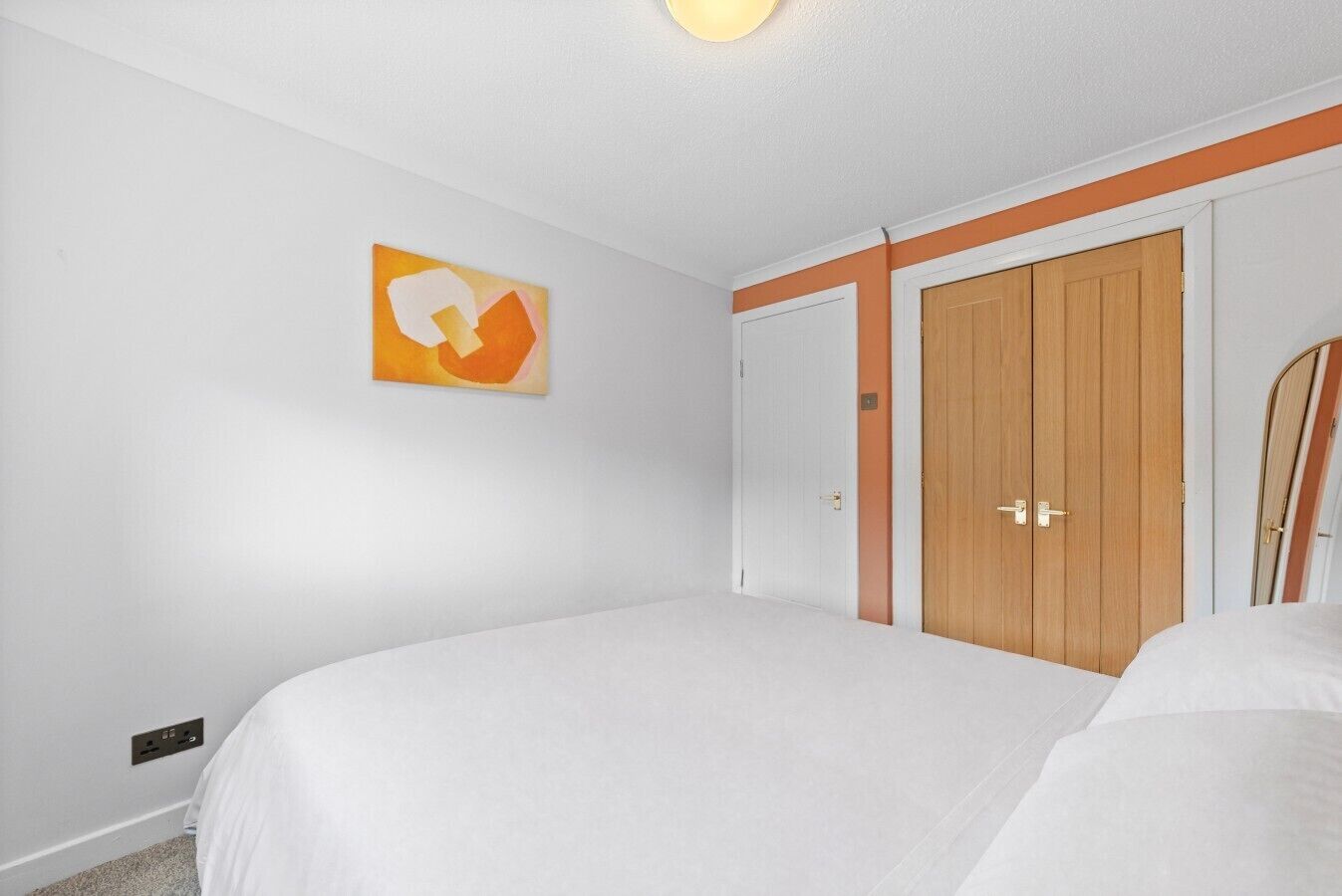 Ein Schlafzimmer mit einem Bett, einem Kleiderschrank und einem an der Wand hängenden Kunstwerk.