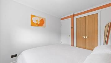 Ein Schlafzimmer mit einem Bett, einem Kleiderschrank und einem an der Wand hängenden Kunstwerk.