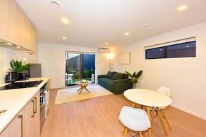 A modern kitchen with a dining area, a sofa, and a window. - The Wellness Nook for a Relaxing City Stay (Christchurch)