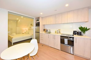 A modern kitchen with a dining area, a refrigerator, a stove, and a sink. - The Wellness Nook for a Relaxing City Stay (Christchurch)