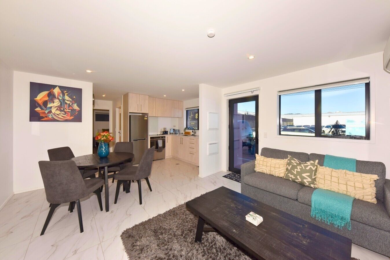 A modern living room with a sofa, coffee table, and dining area.