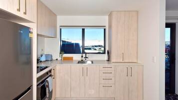 A modern kitchen with a built-in oven, a sink, and a window with a view of a parking lot.