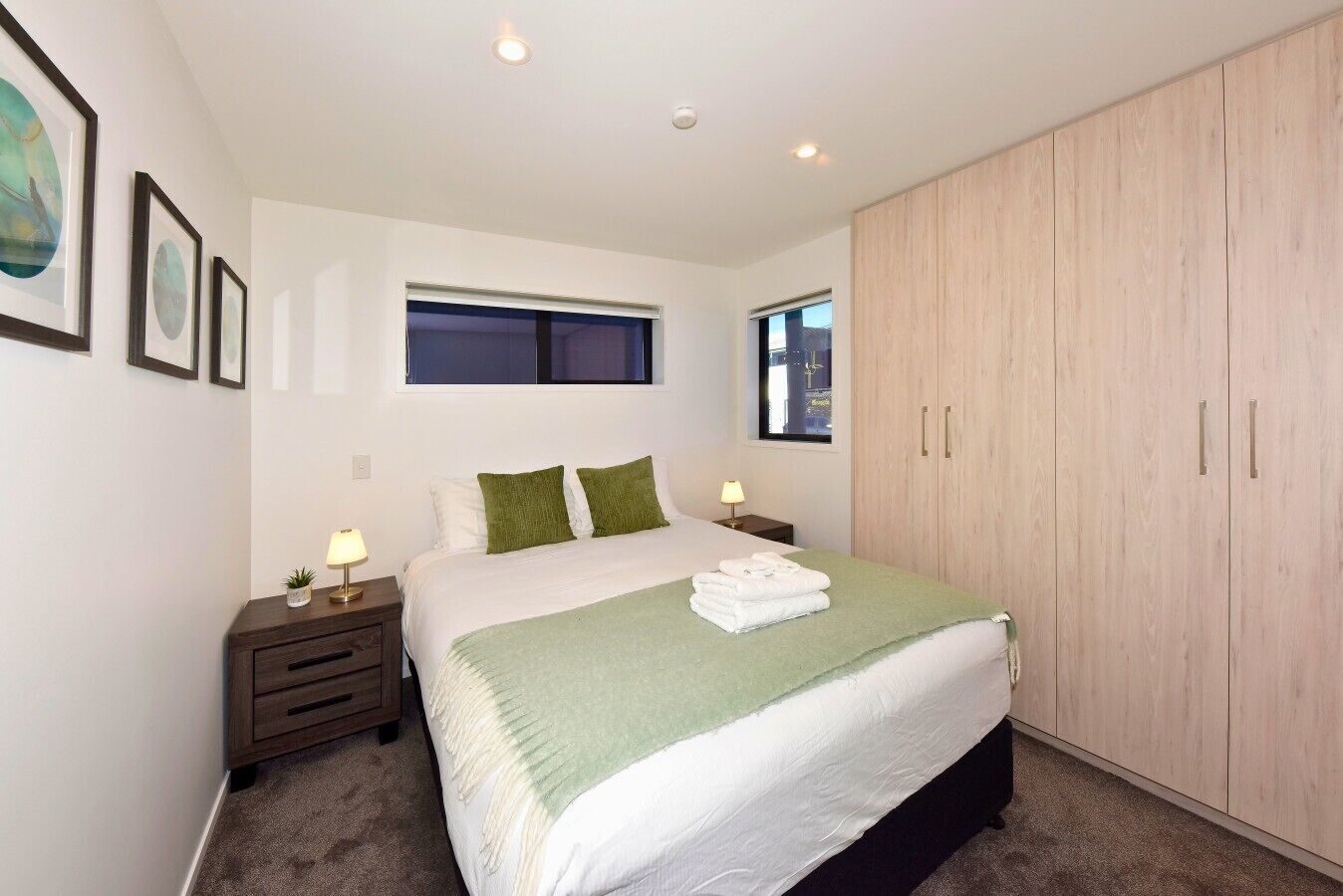A bedroom with a bed, two bedside tables, a window, and a wardrobe.