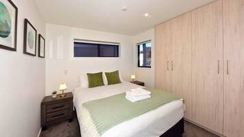 A bedroom with a bed, two bedside tables, a window, and a wardrobe.