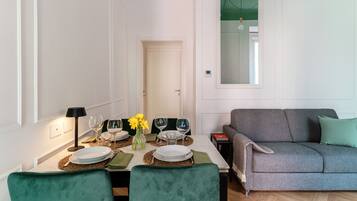 Un comedor con una mesa lista para cuatro personas, un sofá y una ventana con vistas.