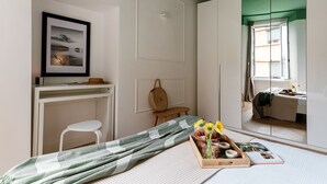 Une chambre à coucher avec un lit, un bureau, une chaise, une fenêtre et une porte.