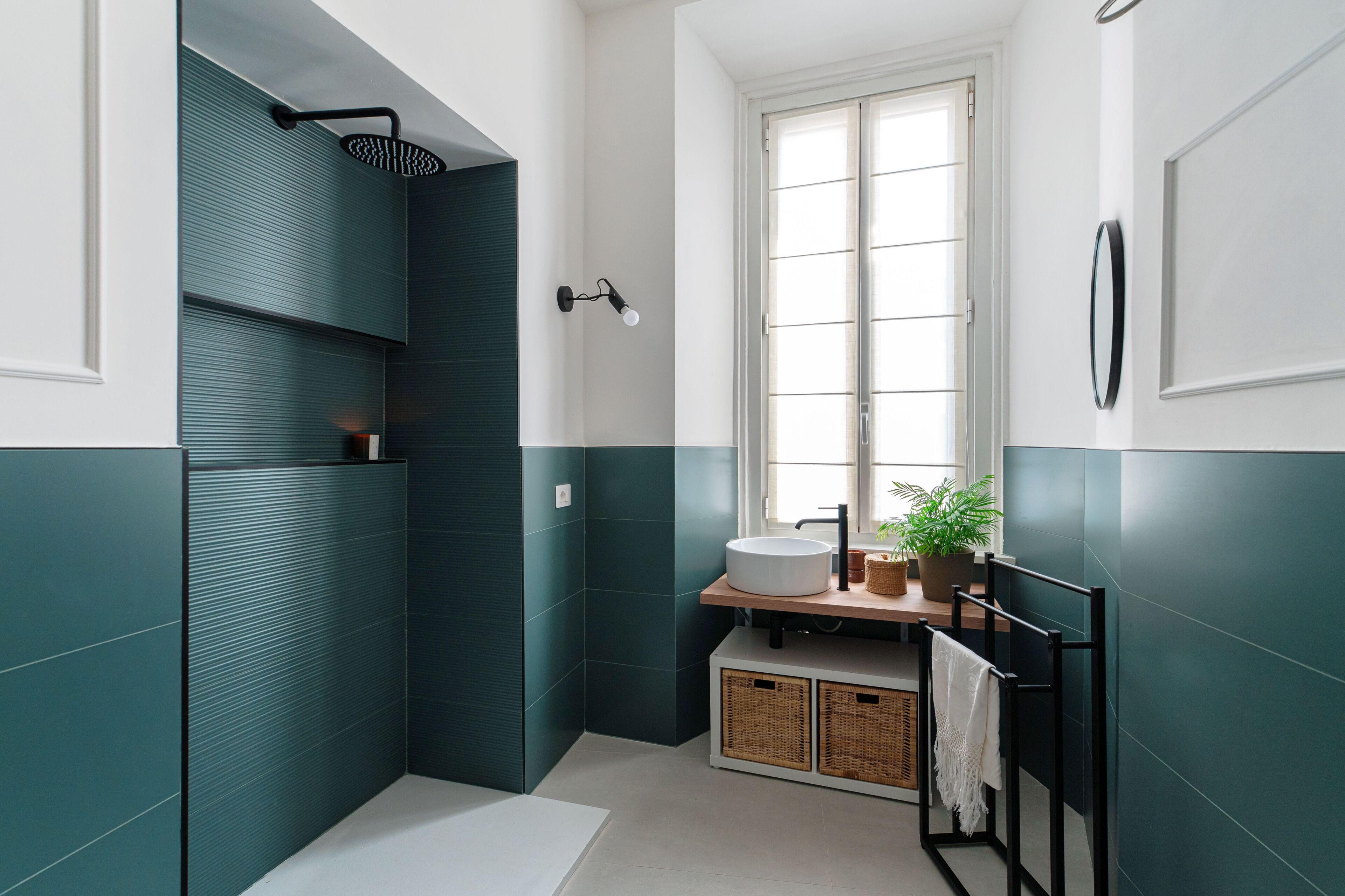 Un baño moderno con ducha, lavabo, ventana y espejo.