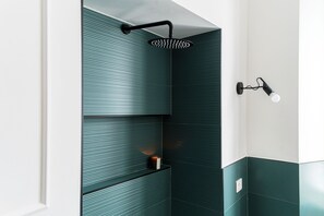 Un baño con ducha, un perchero y una repisa con una vela.