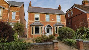 A two-story brick house with a front garden, a bay window, and a conservatory.