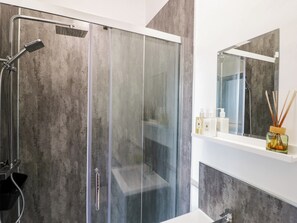 A modern bathroom with a glass shower enclosure, a white sink, and a mirror above the sink. - Astwood House (Malvern)