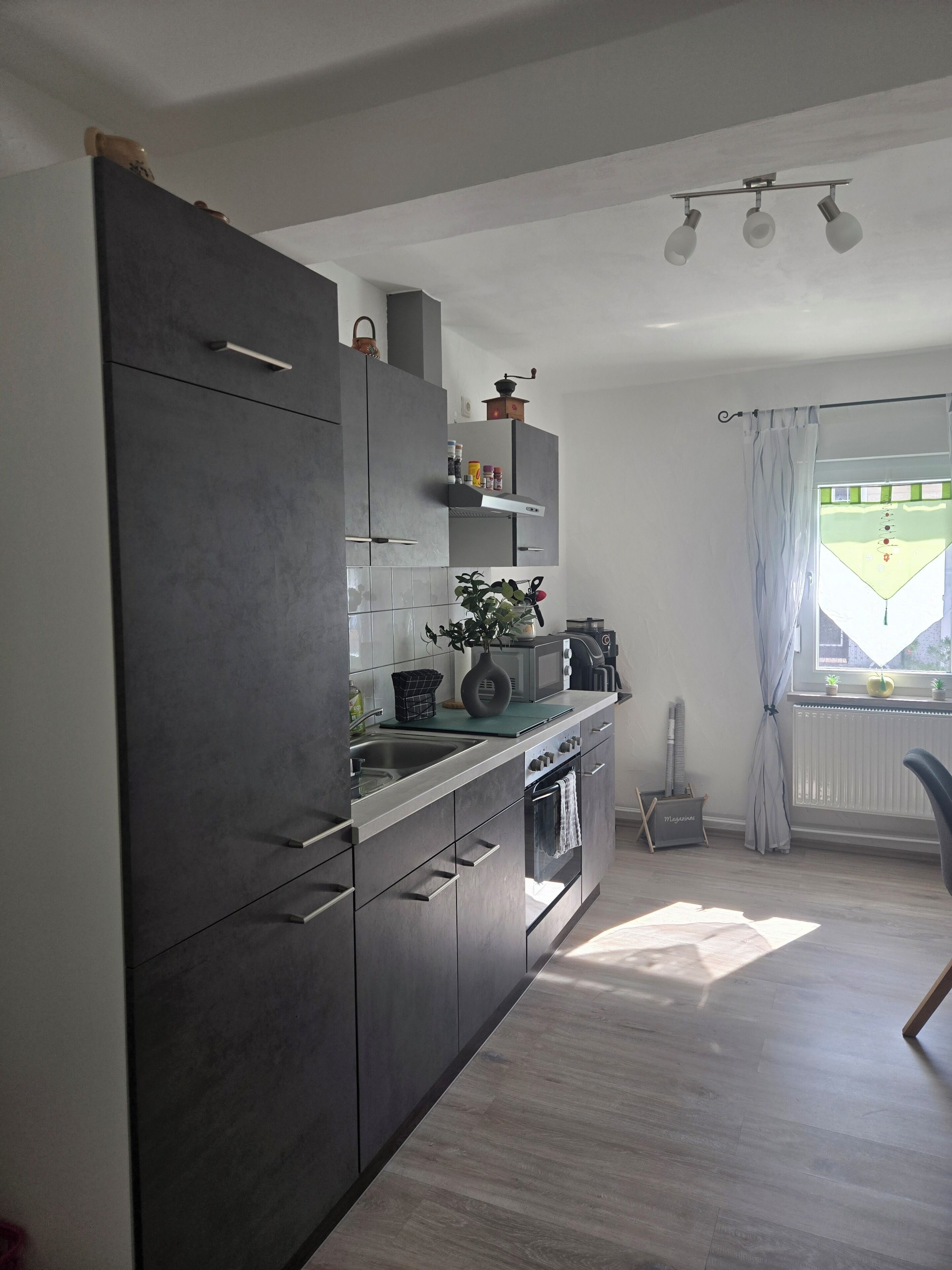 Eine moderne Küche mit Einbauofen, Mikrowelle und Spüle. Ein Fenster bietet Blick ins Freie.