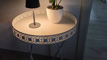 Een kleine ronde tafel met een lamp en een bloempot.