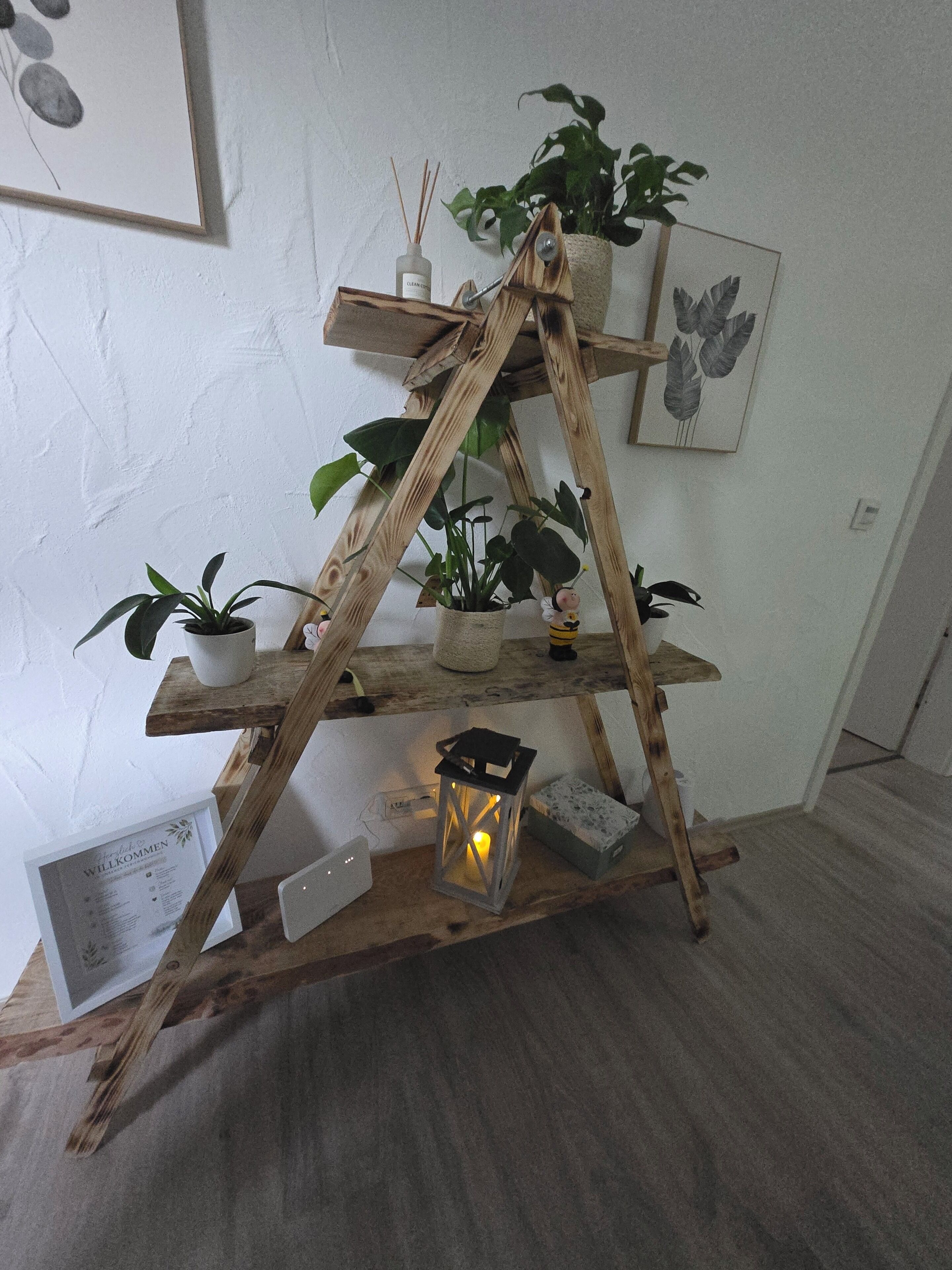 Un soporte de madera con varias repisas que sostienen macetas y un farol.