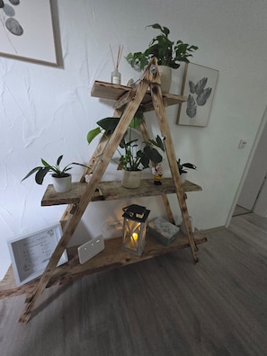 A wooden plant stand with multiple shelves holding potted plants and a lantern.