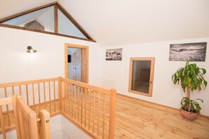 A wooden staircase with a handrail leading to an upper floor, a potted plant, and two framed photographs on the wall. - Key to Heaven - Glacier Apartments (Flattach)