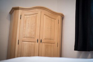 Une armoire en bois à deux portes et au sommet incurvé, ornée de motifs sculptés représentant des fleurs.