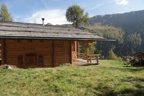 Eine Holzhütte mit Veranda, eingebettet in eine gebirgige Landschaft.