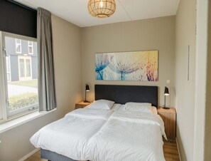 A bedroom with a large bed, two bedside tables, a window with curtains, and a wall-mounted artwork. - Harbour Villa in the Heart of Friesland (Heeg)
