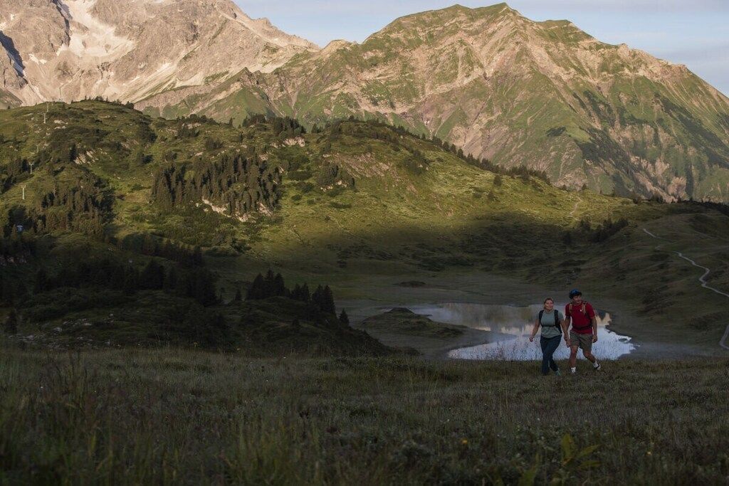 Un paysage montagneux avec un lac et des randonneurs.