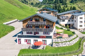 Ein mehrstöckiges Gebäude mit Balkon, einer Steinsichtmauer und einem Parkplatz.