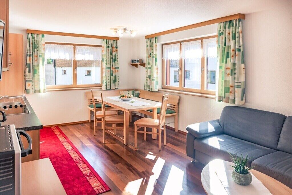 Een compacte leefruimte met een eethoek, een bank en een kitchenette.