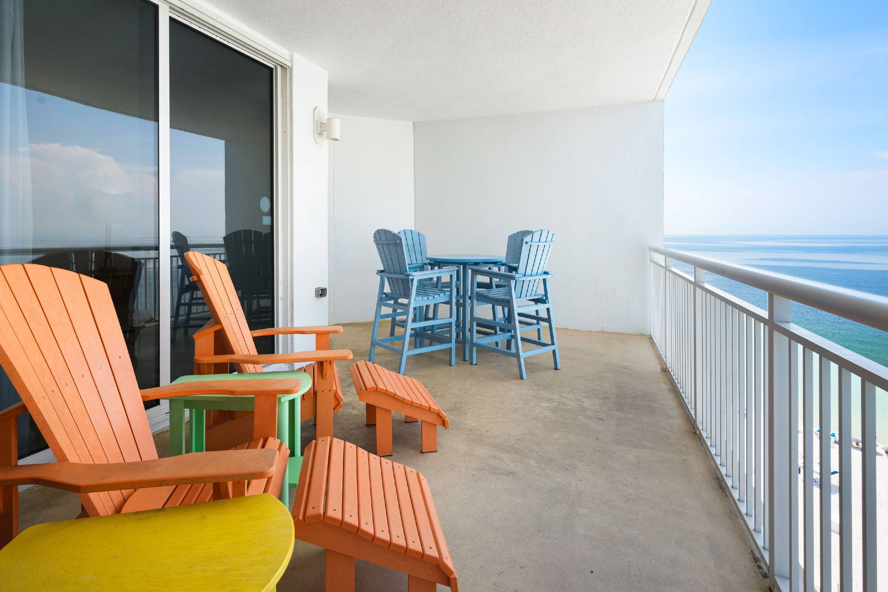 Ein Balkon mit Blick auf den Ozean, ausgestattet mit Gartenmöbeln inklusive Stühle und Tische.